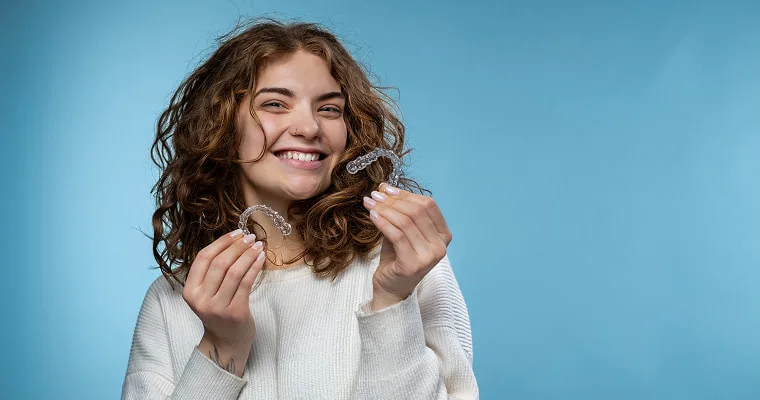 A woman is holding Invisalign trays