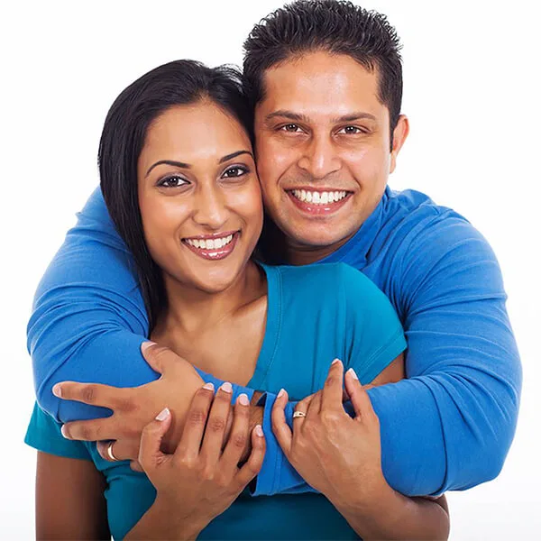 A middle-aged couple embrace and smile after her cosmetic dental treatment.